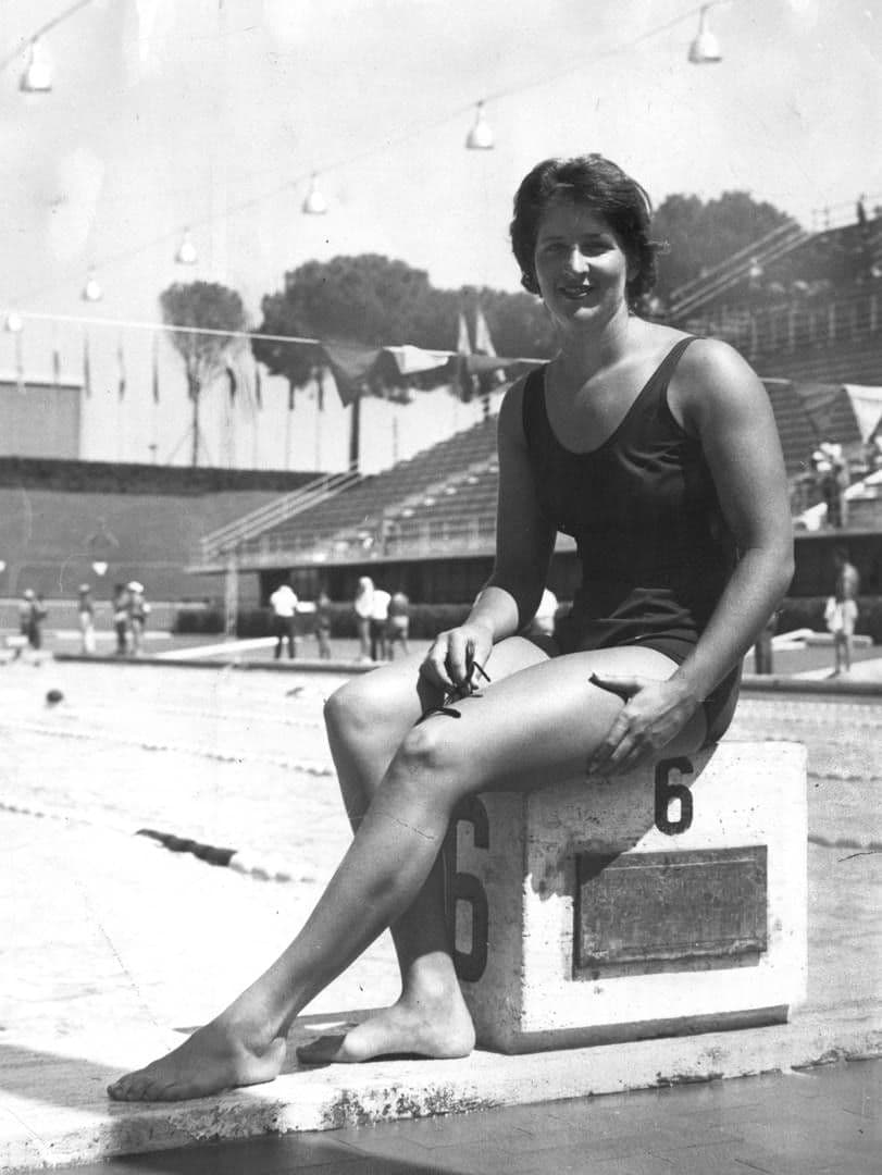 A swimmer sitting on a starting block at a 1960s international pool