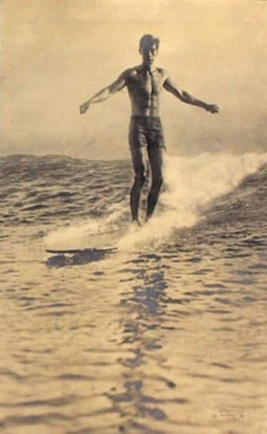 Duke Kahanamoku riding a surfboard, early 20th century